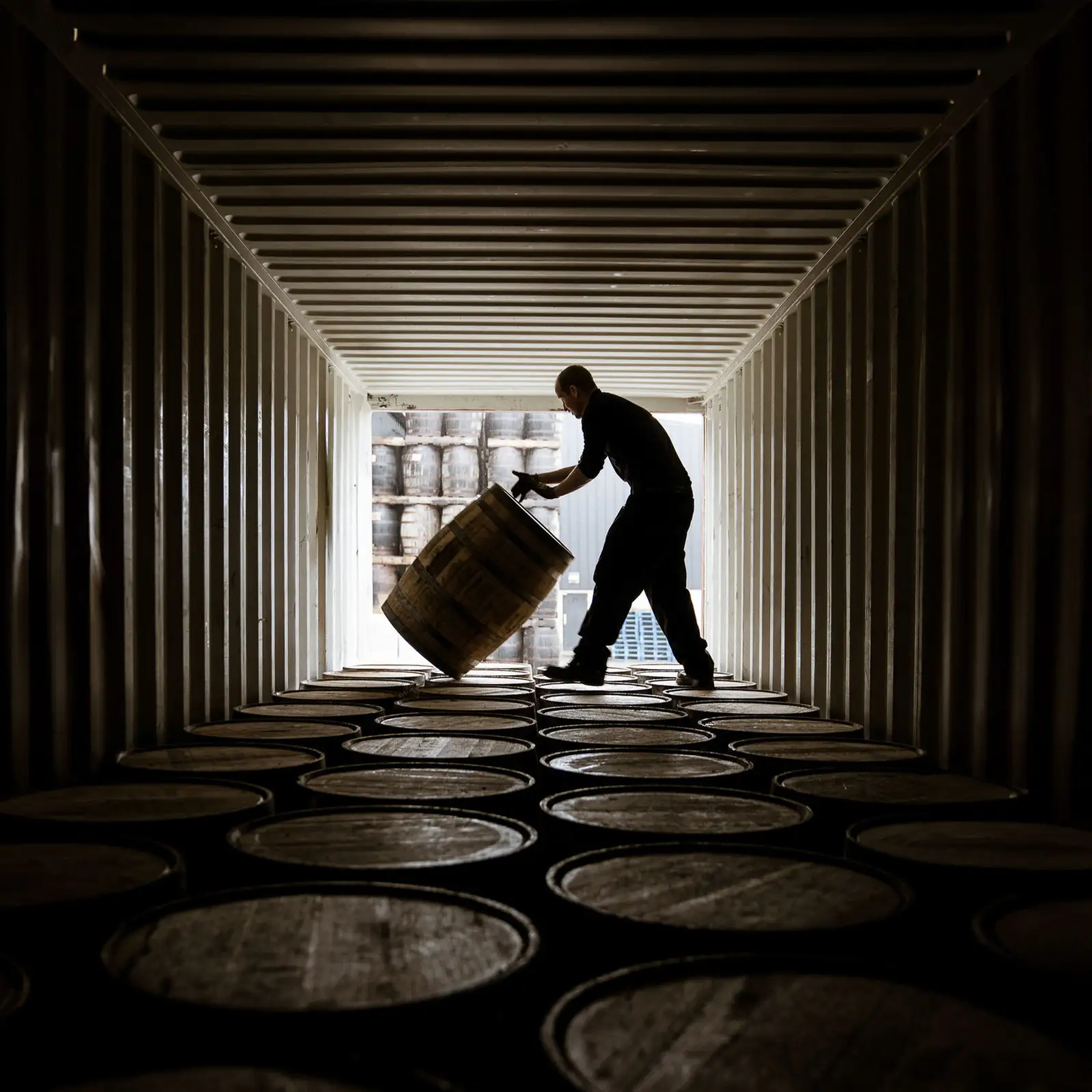 West Cork Distillers oak barrels stacked in warm warehouse light